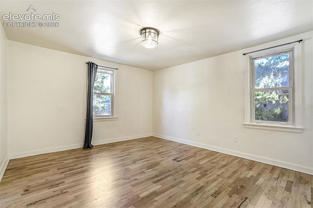 Image 13 of 50: Room featuring wood-finish flooring, two double-hung windows, and a central