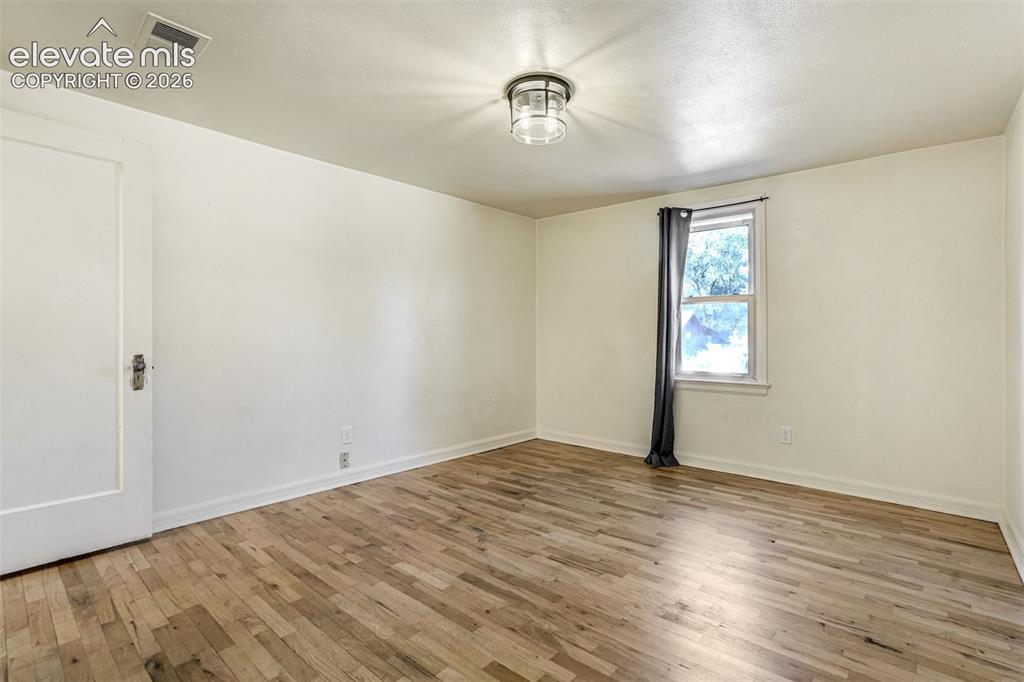 Image 14 of 50: Room featuring wood-finish flooring, a single-pane window, and a flush-moun