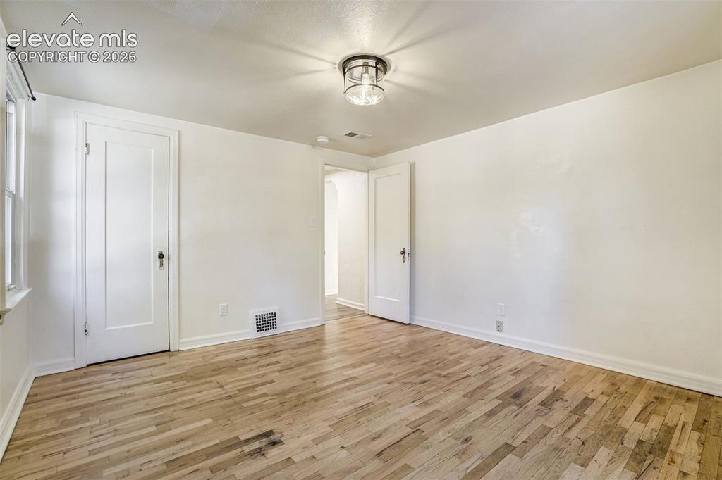 Image 17 of 50: Interior room featuring wood-finish flooring, two classic panel doors with