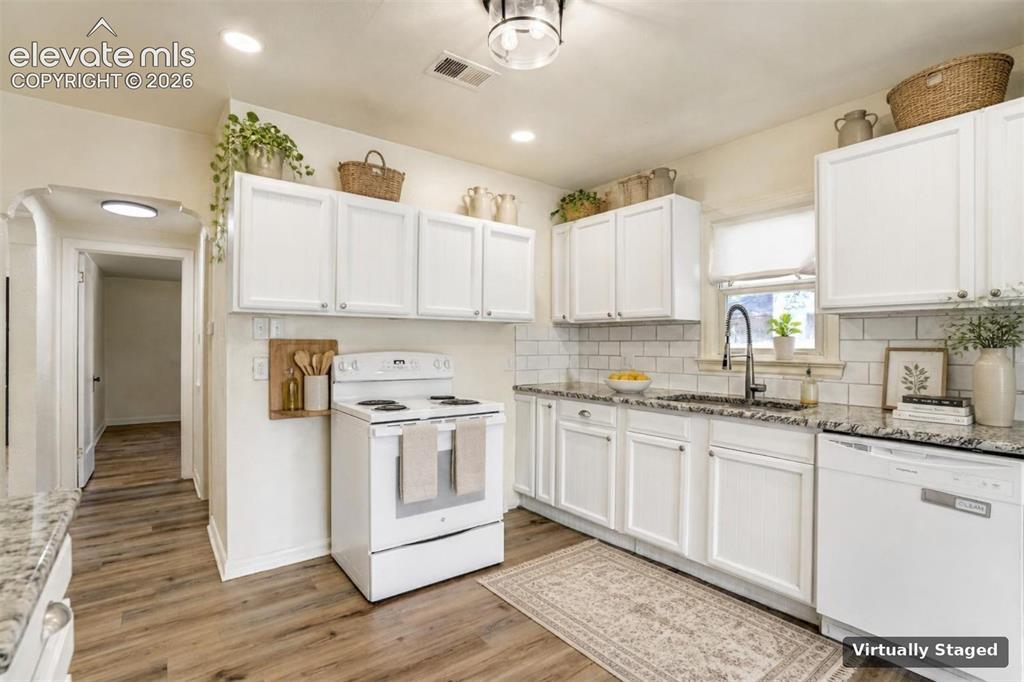 Image 19 of 50: Kitchen featuring shaker-style white cabinetry, stone-finish countertops, s