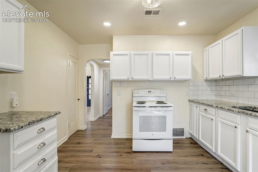 Image 23 of 50: Kitchen featuring white shaker-style cabinetry, stone-finish countertops, s
