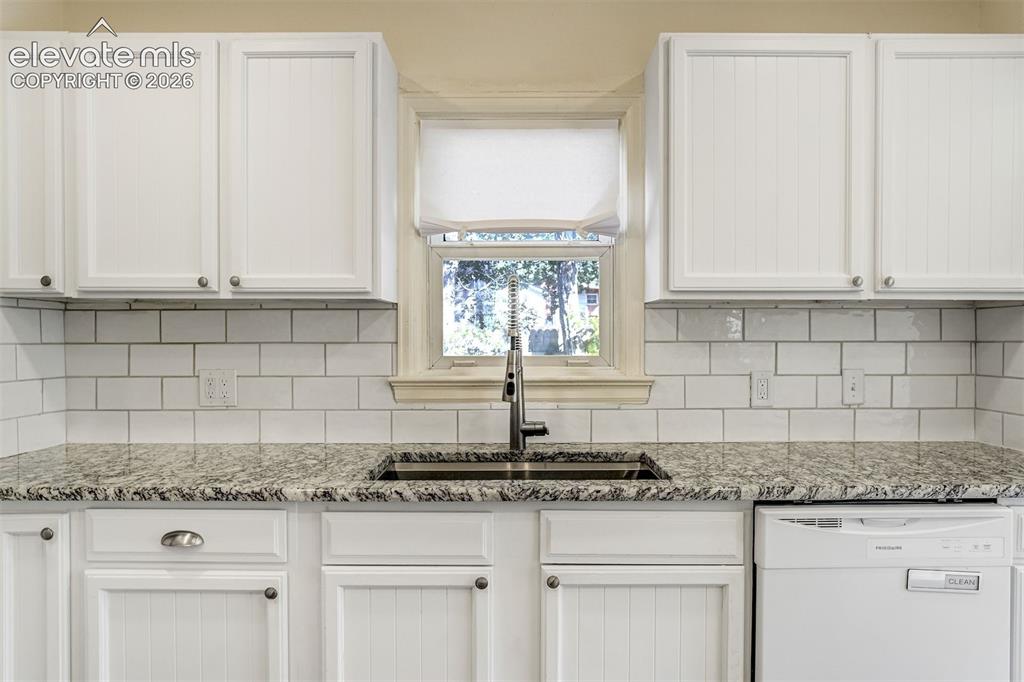 Image 24 of 50: Kitchen featuring white beadboard cabinetry, stone-finish countertops, whit