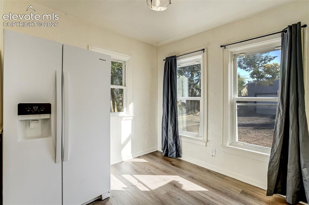 Image 26 of 50: Wood-finish flooring, white side-by-side refrigerator, and multiple windows