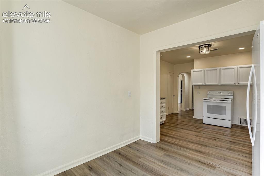 Image 27 of 50: Wood-finish flooring, white cabinetry, recessed lighting, and a flush-mount