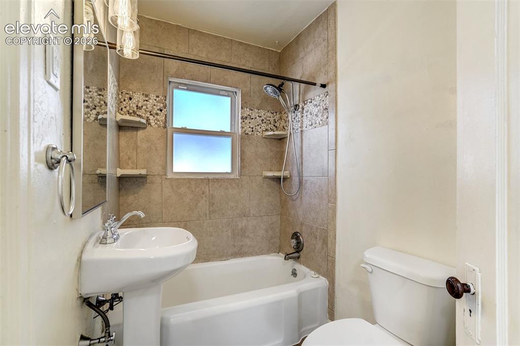 Image 30 of 50: Bathroom featuring a pedestal sink, a bathtub with a tiled surround, integr