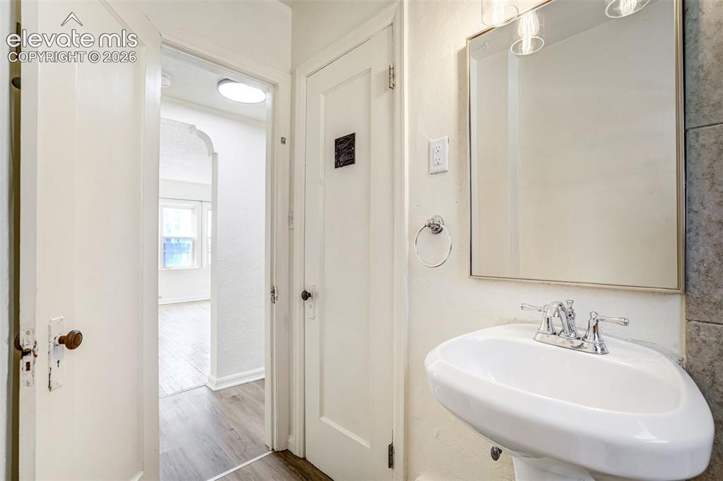 Image 31 of 50: Wall-mounted rectangular mirror, pedestal sink with a chrome dual-handle fa