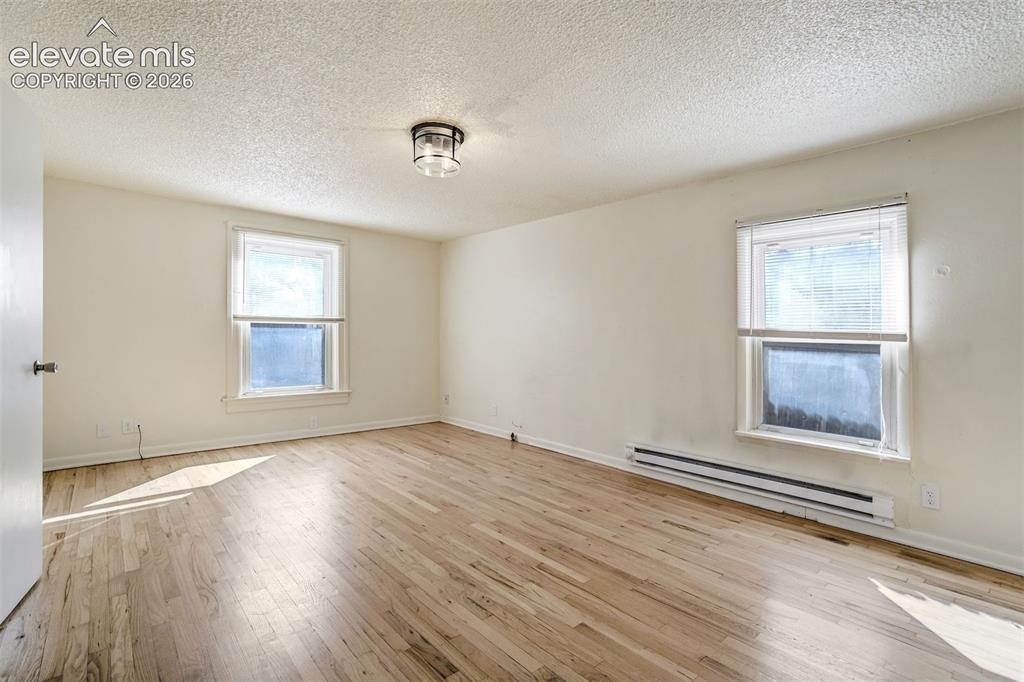 Image 35 of 50: Neutral-toned room featuring wood-finish flooring, two windows with white t