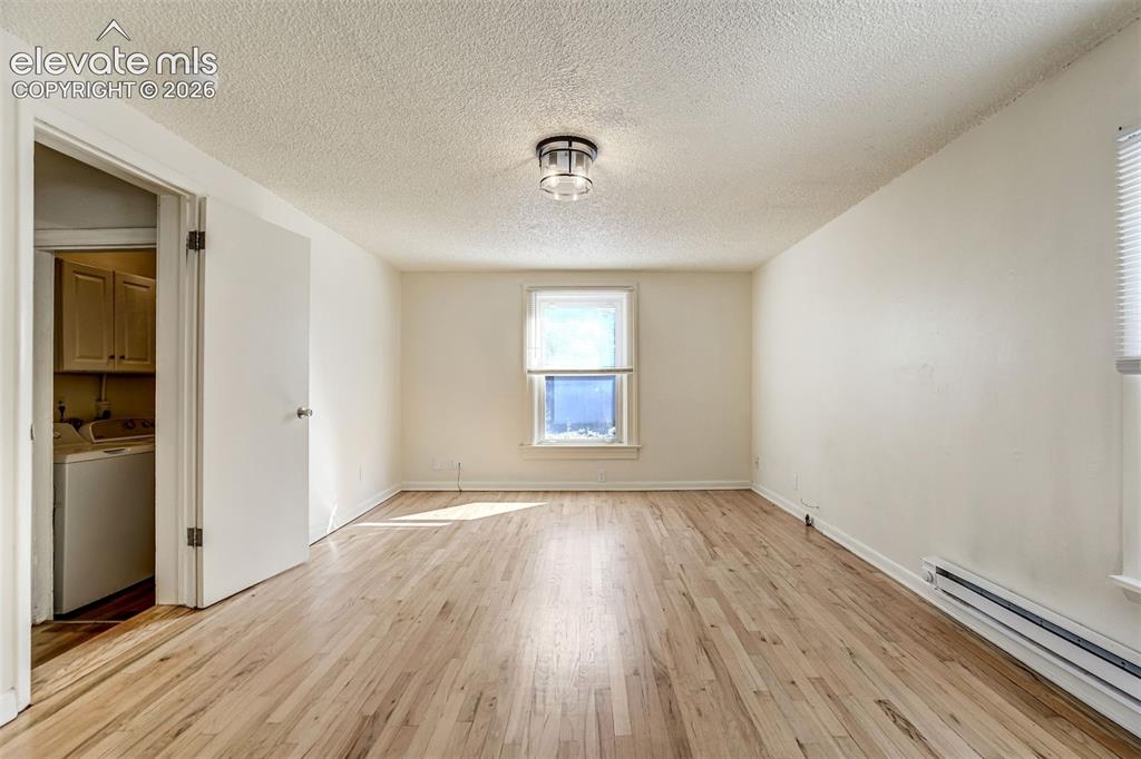 Image 36 of 50: Interior room featuring wood-finish flooring, a central drum-style light fi