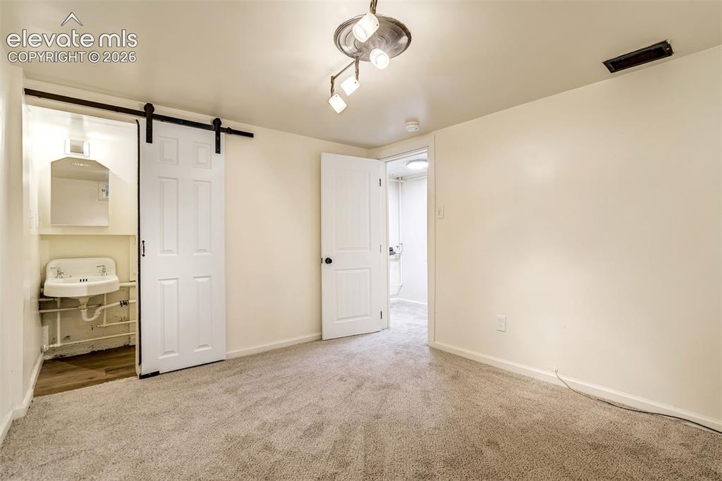 Image 47 of 50: Interior space featuring neutral wall-to-wall carpeting, a sliding barn doo