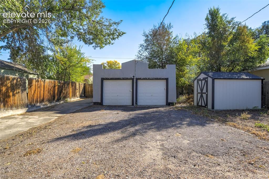 Image 49 of 50: Detached two-car garage featuring a parapet roofline, two roll-up doors, an