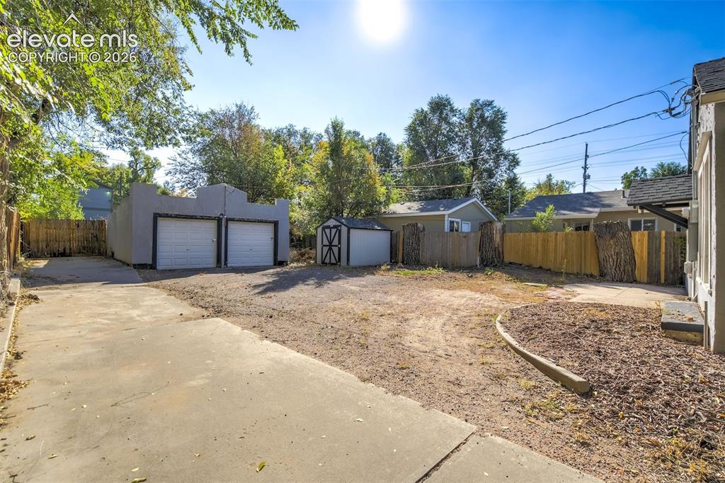 Image 50 of 50: Concrete driveway with a detached two-car garage, secondary storage structu