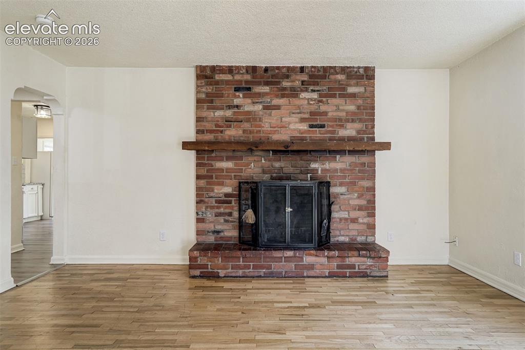 Image 6 of 50: Full-height brick fireplace featuring a wood mantel, raised brick hearth, a