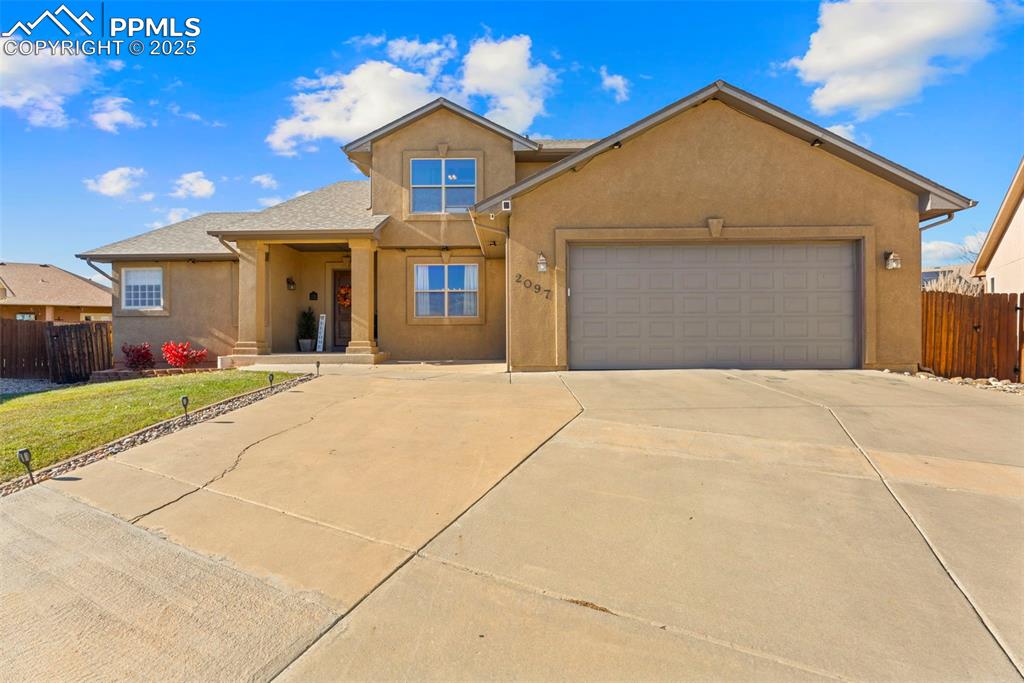 Caption: View of front of home featuring stucco siding, concrete driveway, an attached garage, and a porch