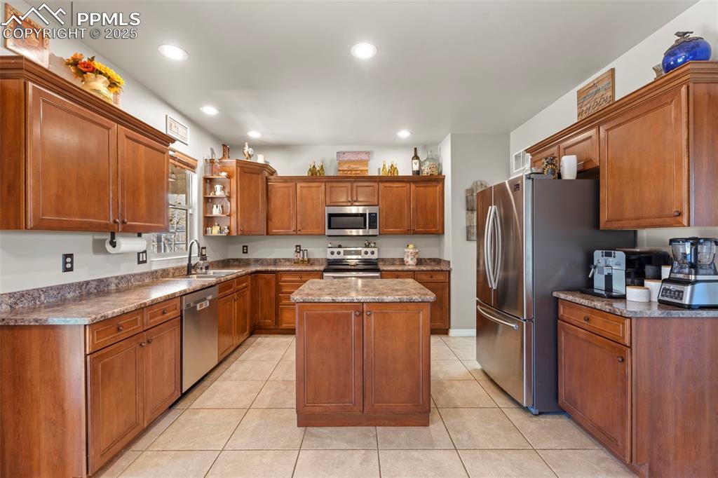 Image 10 of 41: Kitchen featuring brown cabinets, open shelves, a kitchen island, appliance