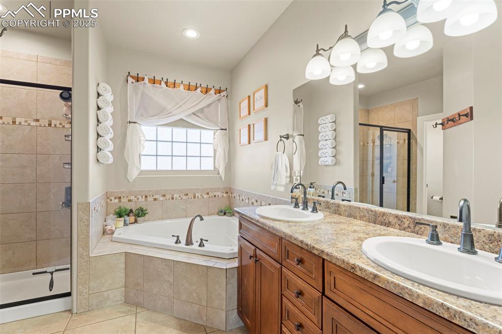 Image 18 of 41: Full bathroom with double vanity, a bath, a stall shower, baseboard heating
