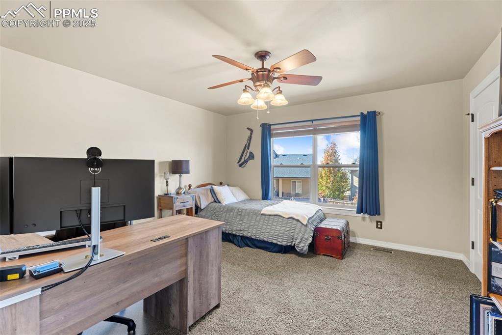Image 19 of 41: Carpeted bedroom with an office area and ceiling fan