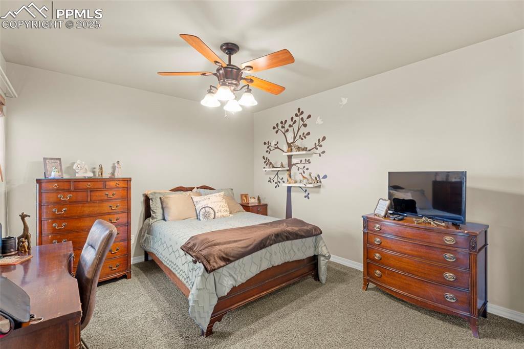 Image 20 of 41: Carpeted bedroom with ceiling fan and a desk
