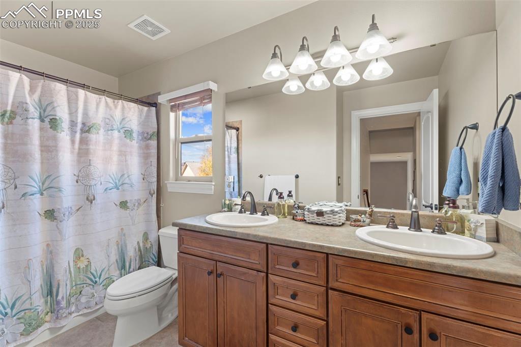 Image 21 of 41: Full bath featuring double vanity, curtained shower, and light tile pattern