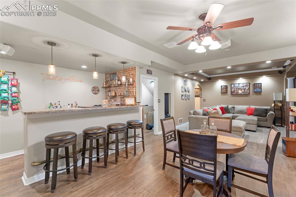 Image 27 of 41: Dining space with light wood-style floors, bar, ceiling fan, a tray ceiling