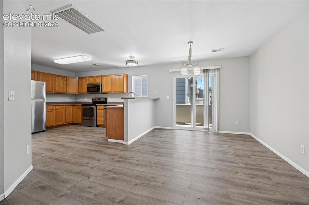 Image 12 of 27: Open-concept kitchen and dining area featuring wood-finish flooring, light