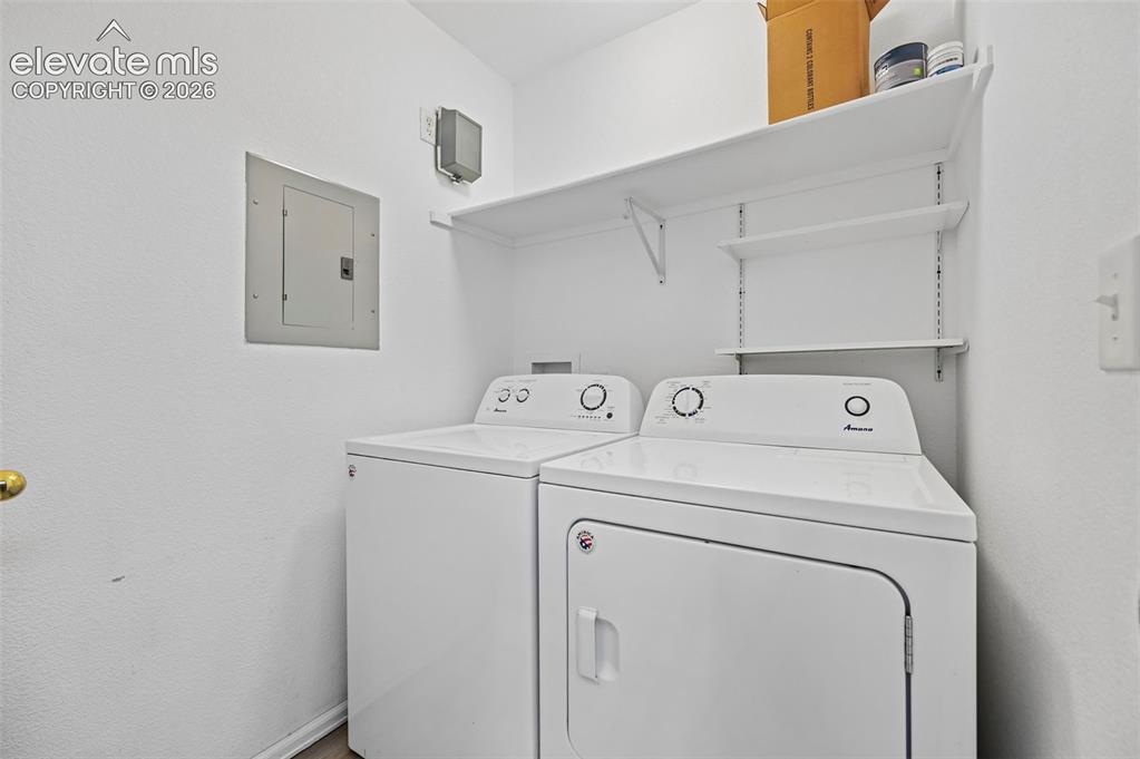 Image 16 of 27: Dedicated laundry area featuring a white electric dryer and top-load washin