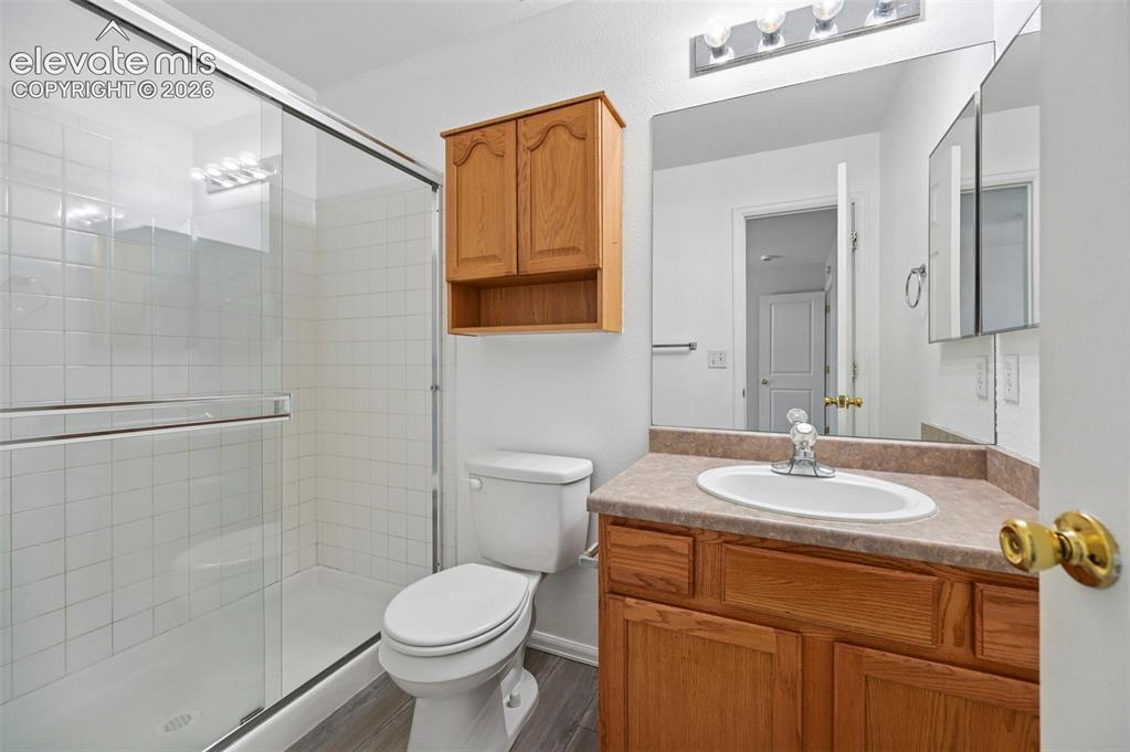 Image 21 of 27: Bathroom featuring a glass-enclosed shower with white tiled walls, a wood-f