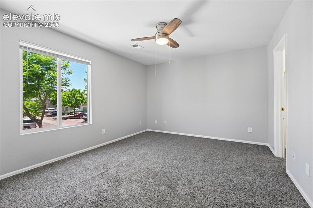 Image 23 of 27: Spacious room with plush gray carpeting, neutral wall tones, a large window