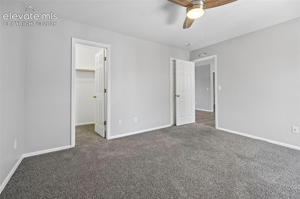 Image 25 of 27: Carpeted room featuring light gray walls, white baseboards, and a wood-fini