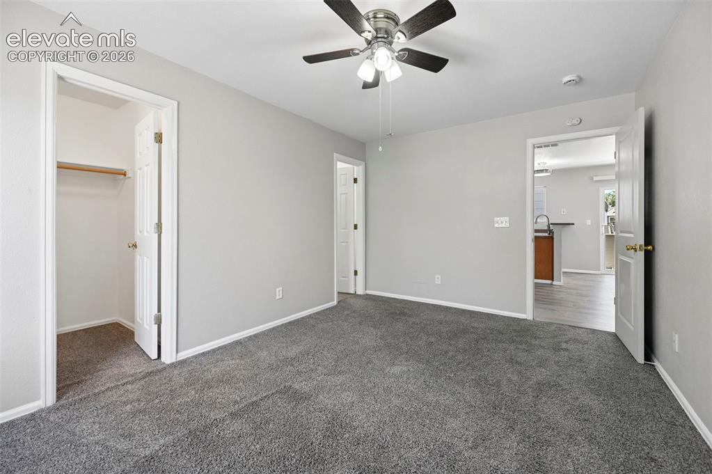 Image 26 of 27: Carpeted room featuring light gray walls, white trim, a ceiling fan with in