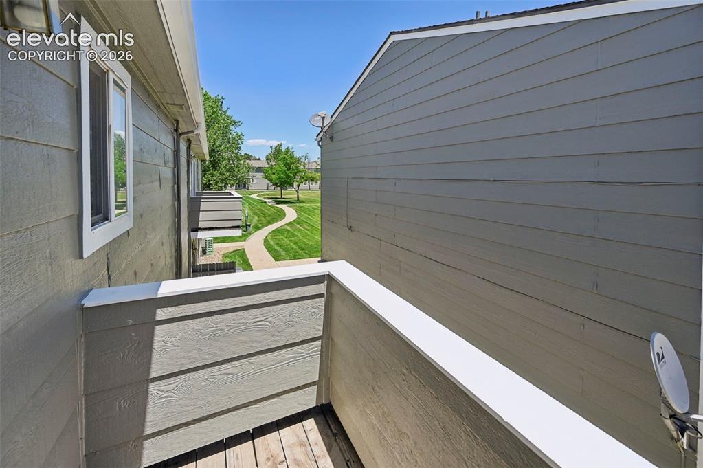 Image 27 of 27: Outdoor balcony with wood-finish flooring and solid panel railing