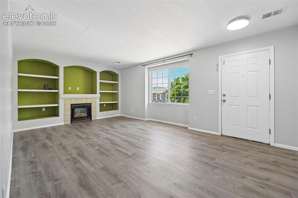 Image 9 of 27: Living area featuring wood-finish flooring, a white paneled entry door, and
