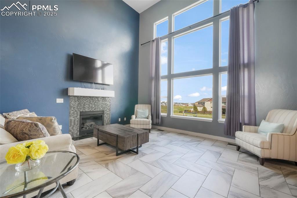 Image 18 of 50: Main level living room with fireplace, large windows and access to upper de