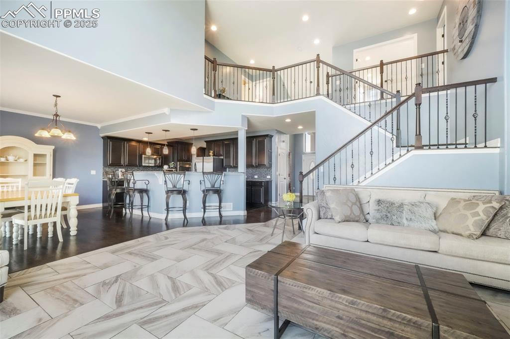 Image 19 of 50: Main level living room with fireplace, large windows and access to upper de