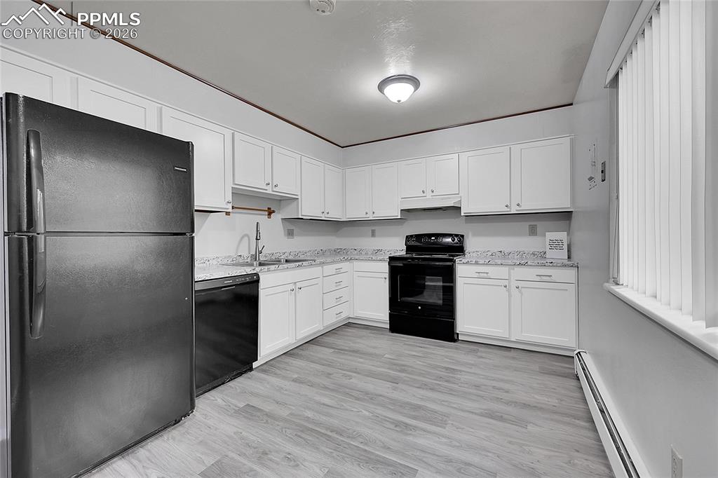 Image 20 of 27: Kitchen featuring black appliances, a baseboard heating unit, white cabinet