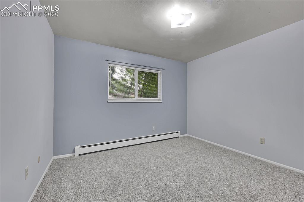 Image 22 of 27: Empty room with a baseboard heating unit and carpet