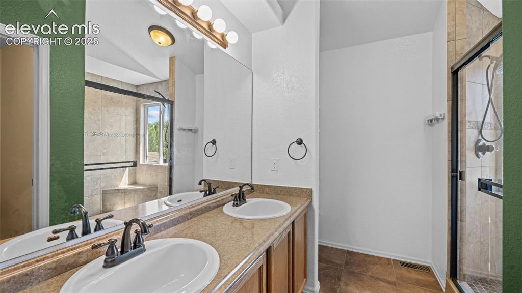 Image 20 of 50: Primary bath with dual sinks and walk-in shower with dual shower heads.