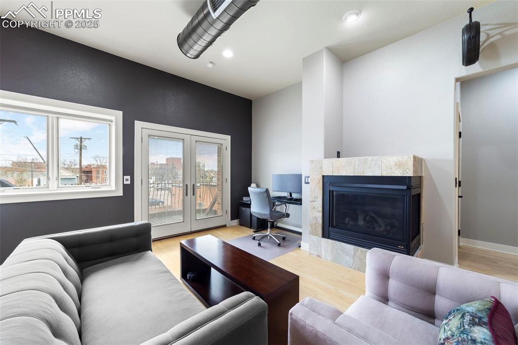 Image 13 of 40: Living room featuring a tiled fireplace, french doors, hardwood floors, an 