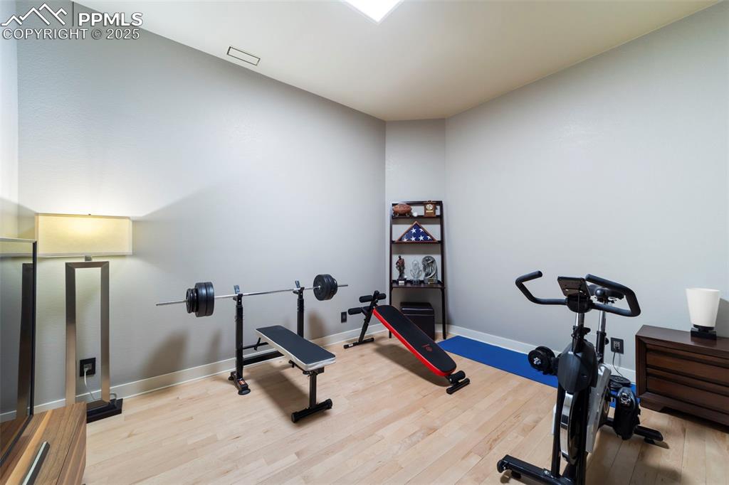 Image 25 of 40: Large bedroom is currently being used as a gym featuring hardwood floors