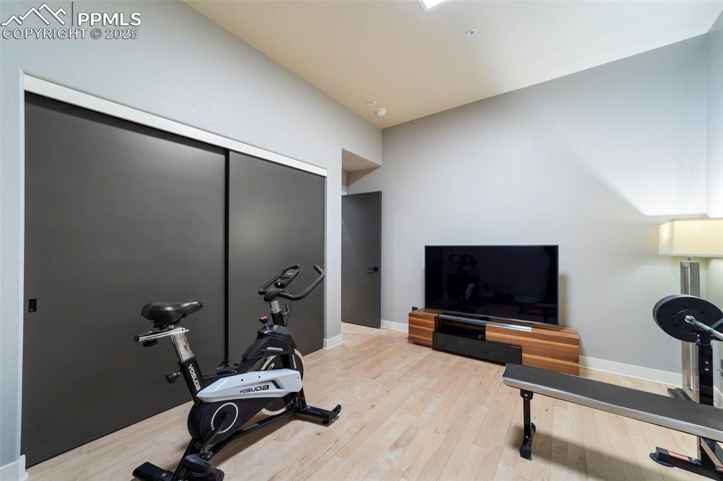 Image 26 of 40: Large bedroom is currently being used as a gym featuring hardwood floors