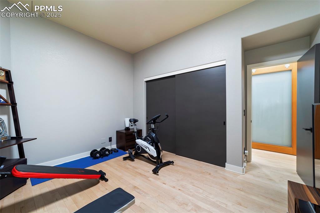 Image 27 of 40: Large bedroom is currently being used as a gym featuring hardwood floors