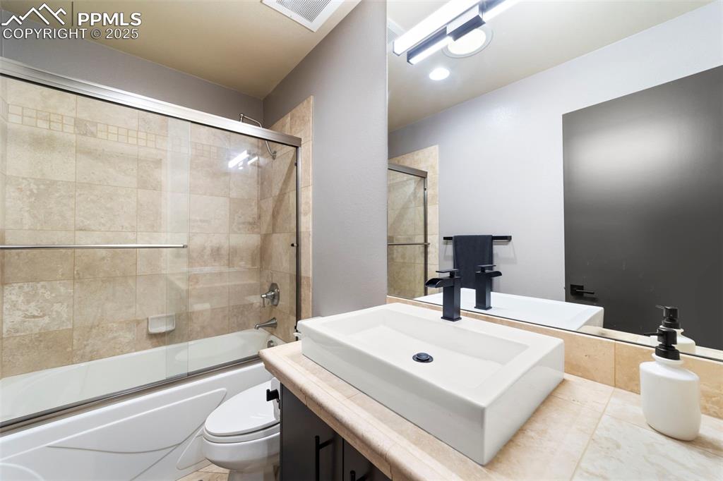 Image 28 of 40: Full secondary bathroom featuring vanity and combined bath / shower with gl