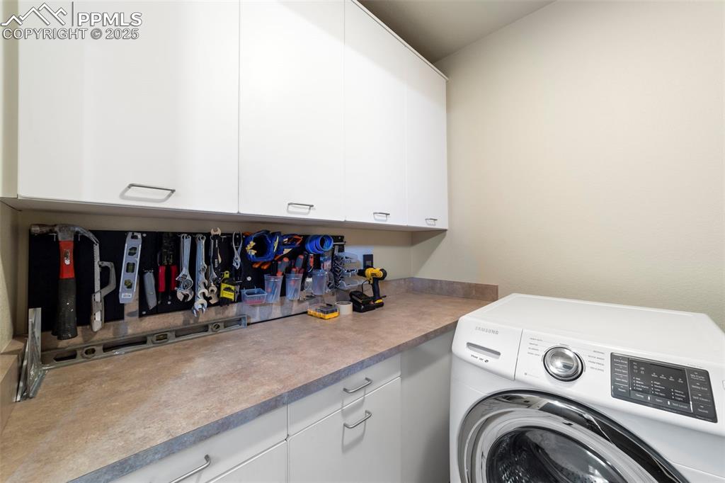 Image 29 of 40: Washroom with washer / dryer and cabinet space and work area