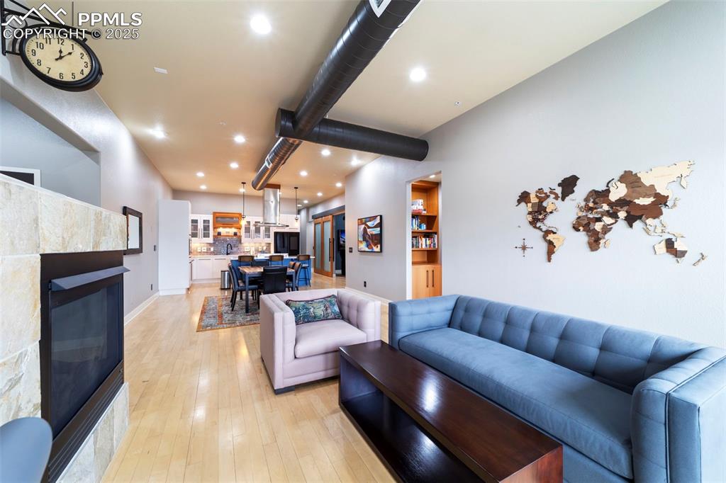 Image 4 of 40: Living area with a tile fireplace, recessed lighting, and hardwood floors.