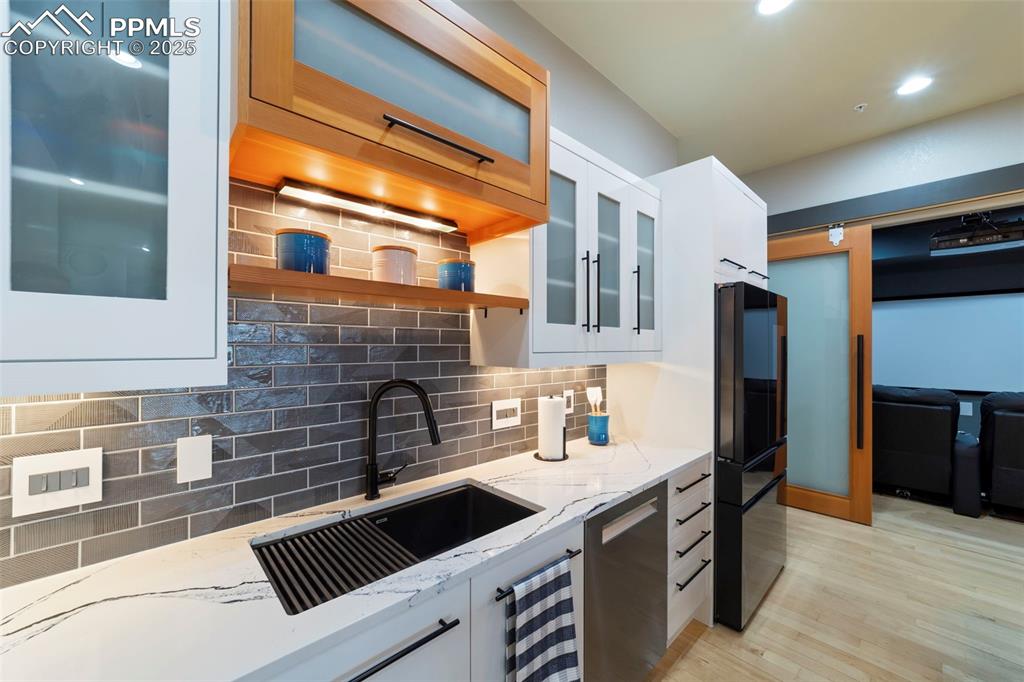 Image 8 of 40: Kitchen featuring white cabinets, decorative backsplash, glass insert cabin