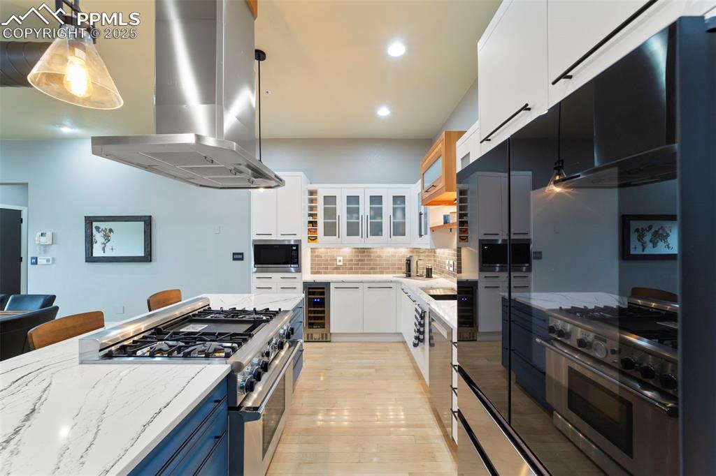 Image 9 of 40: Kitchen with white cabinetry, Thermador range/oven with vent hood, stainles