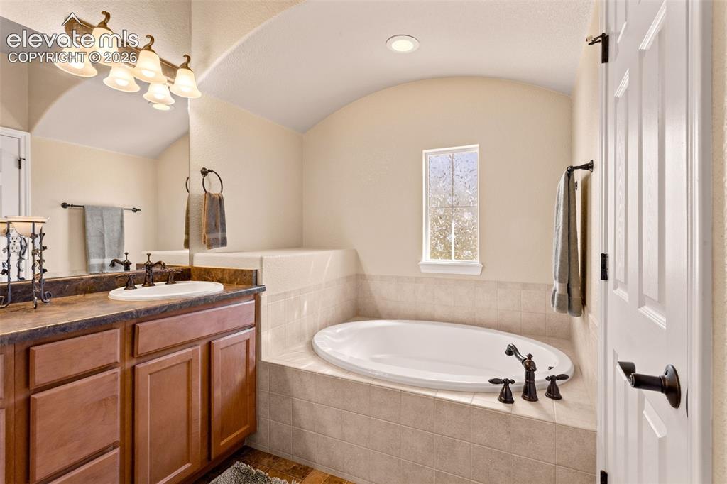 Image 16 of 26: Bathroom featuring an integrated soaking tub with tiled surround, a single 