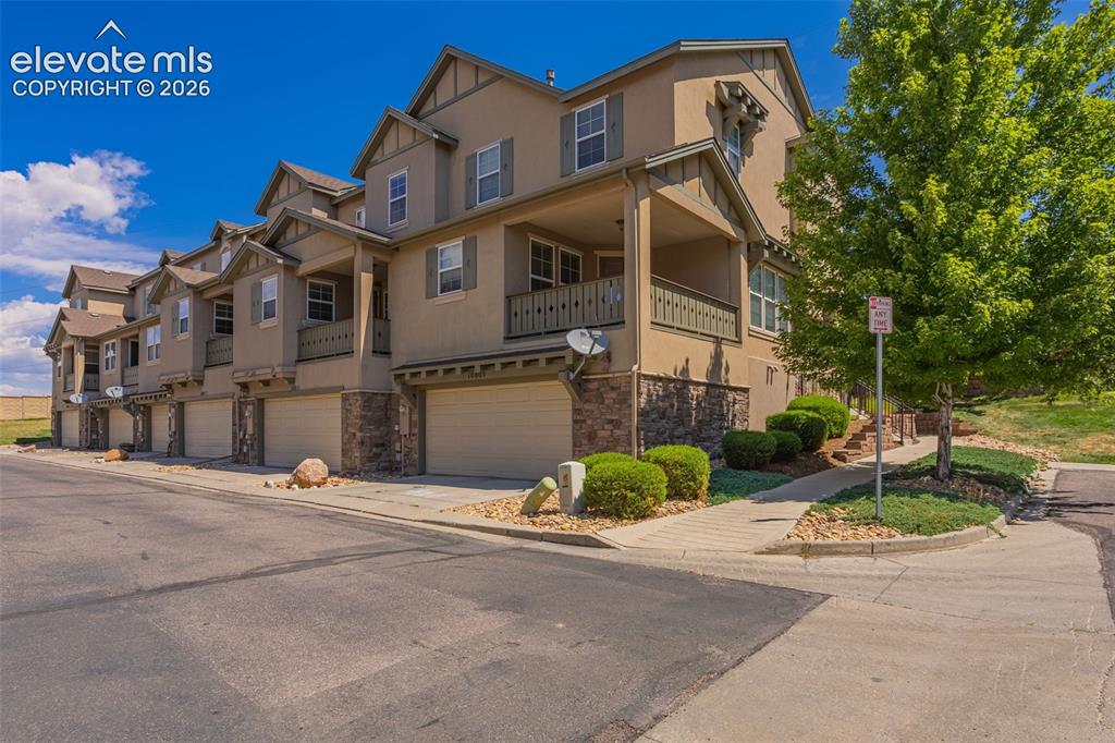 Image 20 of 26: Multi-story townhome exterior featuring stucco siding, stone accents, multi