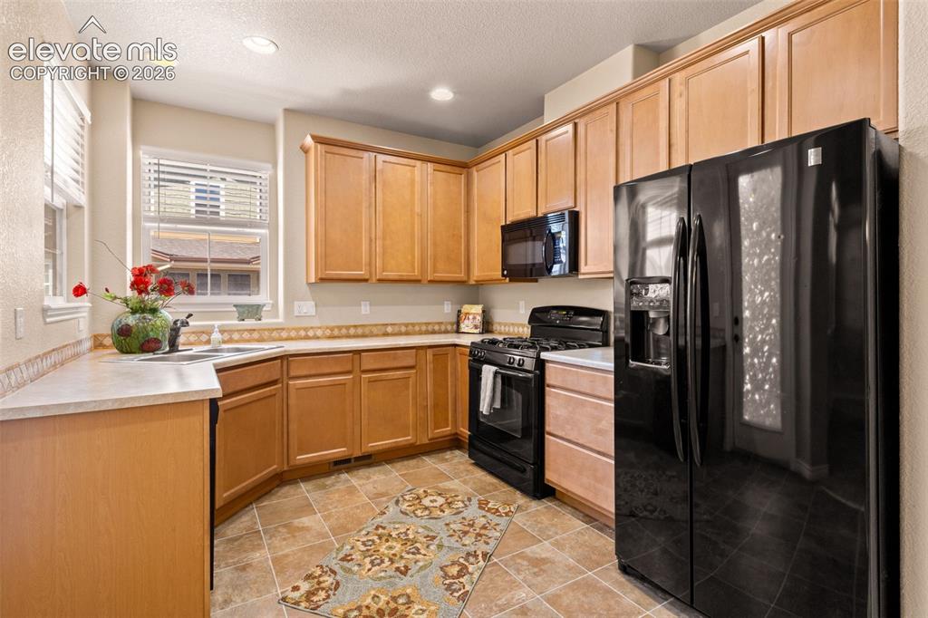 Image 4 of 26: Kitchen featuring wood cabinetry, integrated black appliances, a double bas