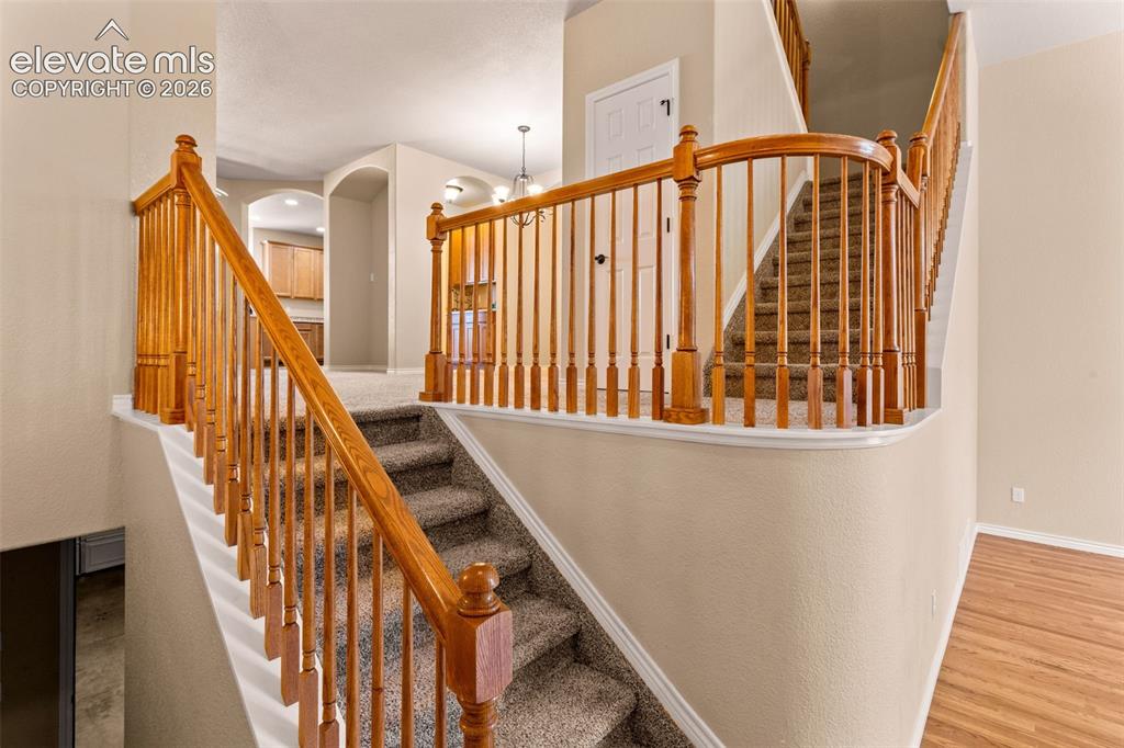 Image 9 of 26: Dual staircase featuring rich wood banisters, carpeted treads, and neutral 