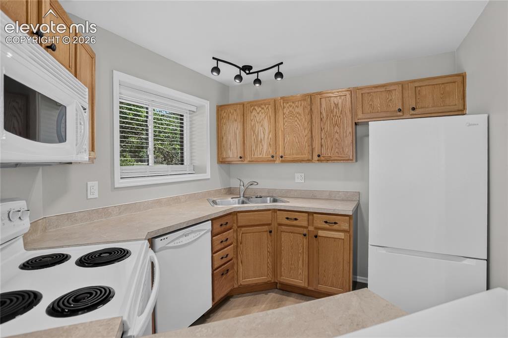 Image 22 of 44: Kitchen featuring wood-finish cabinetry, solid surface countertops, a white